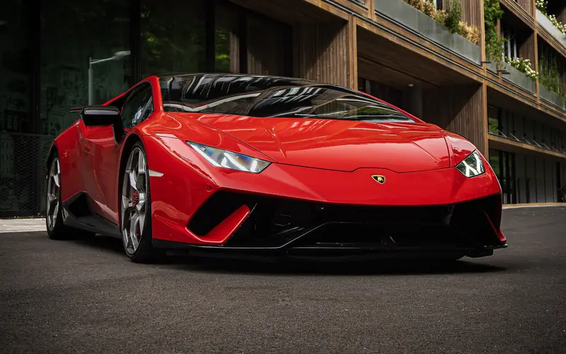 Lamborghini Huracán Performante rouge vue de trois quarts avant, devant un immeuble aux balcons végétalisés.