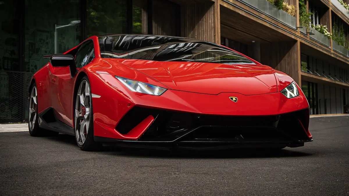 Lamborghini Huracán Performante rouge vue de trois quarts avant, devant un immeuble aux balcons végétalisés.