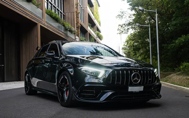 Mercedes-AMG A45 S noire, vue trois-quarts avant gauche, dans une rue bordée d'immeubles.