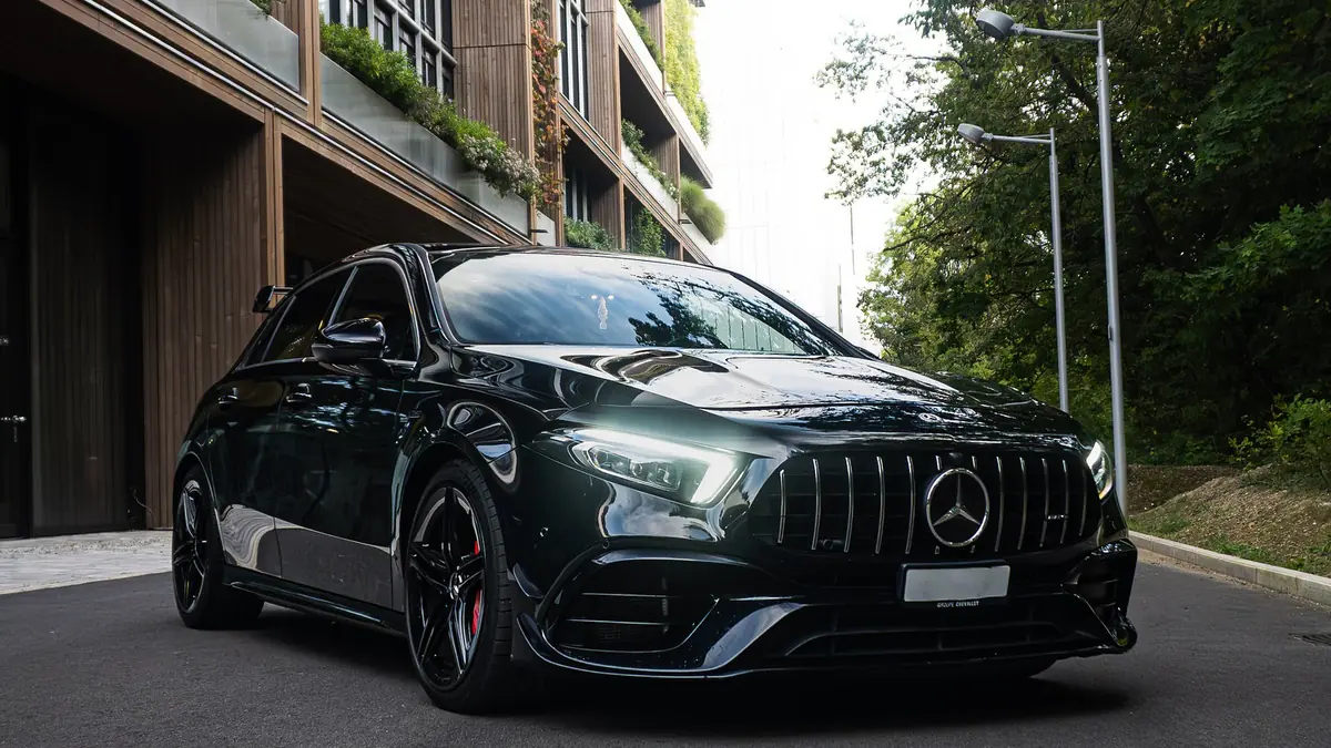 Mercedes-AMG A45 S noire, vue trois-quarts avant gauche, dans une rue bordée d'immeubles.