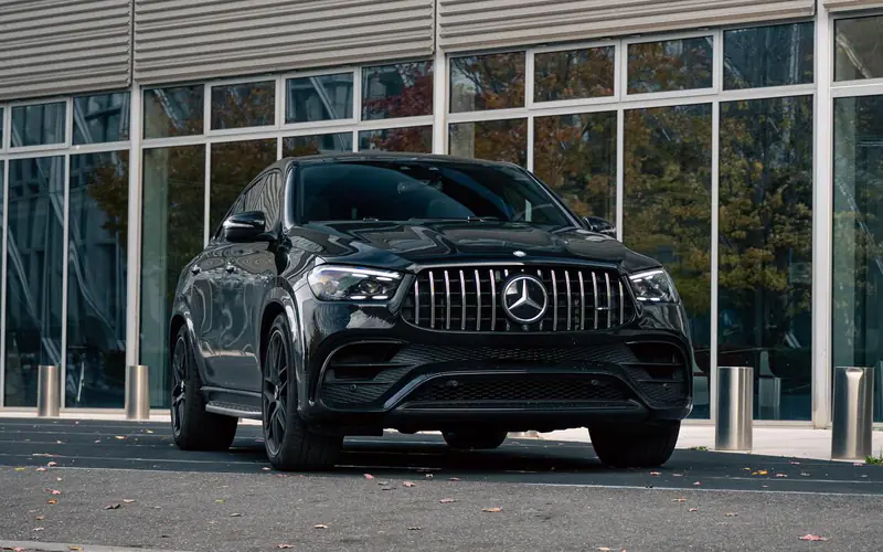 Mercedes-AMG GLE 63 S Coupé noir, vue trois-quarts avant côté gauche, devant une façade vitrée.