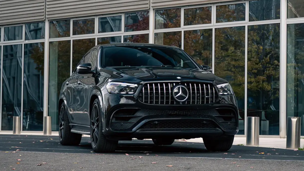 Mercedes-AMG GLE 63 S Coupé noir, vue trois-quarts avant côté gauche, devant une façade vitrée.
