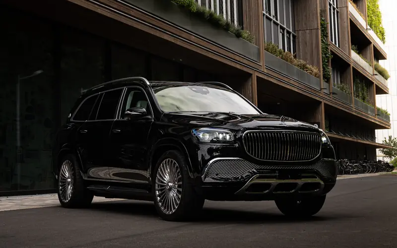 Mercedes-Maybach GLS 600 noir vu de trois quarts avant, a l'arret devant un immeuble contemporain.