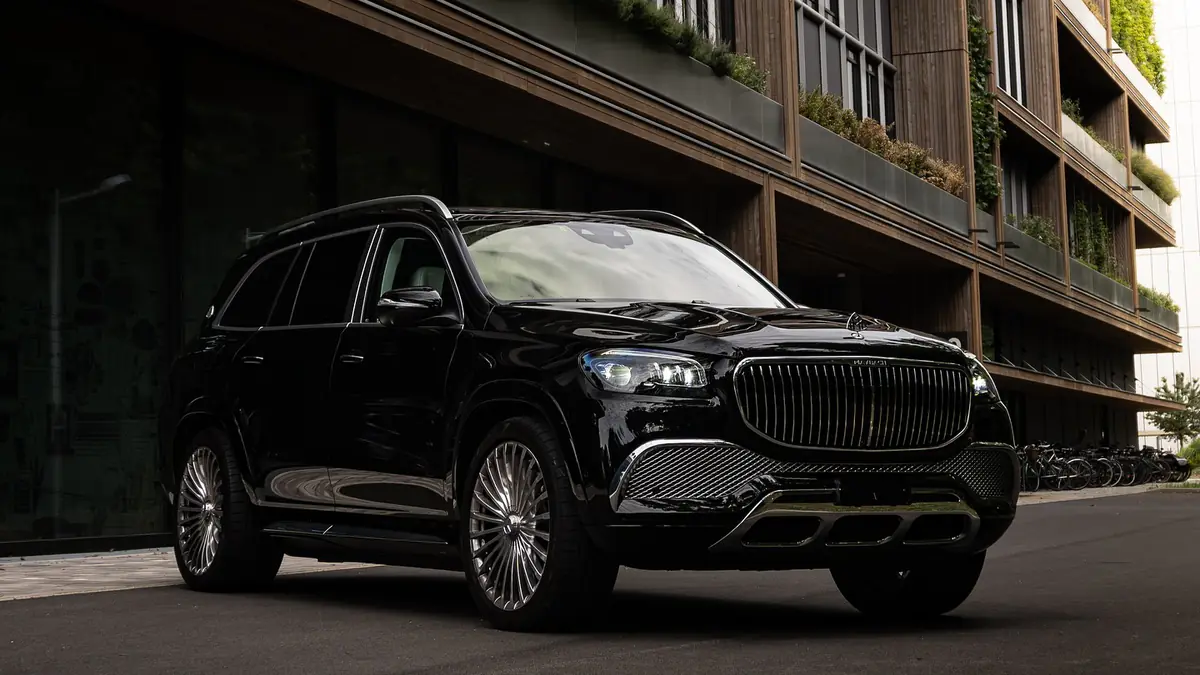 Mercedes-Maybach GLS 600 noir vu de trois quarts avant, a l'arret devant un immeuble contemporain.