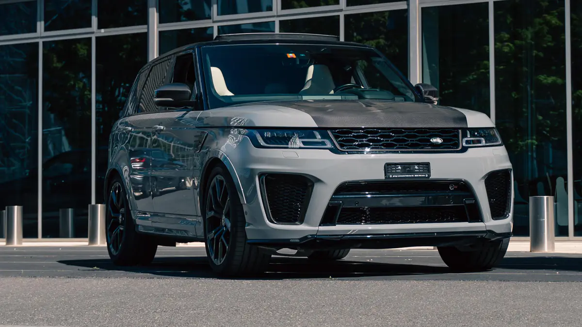 Range Rover Sport SVR gris Nardo Grey vu de trois quarts avant, à l'arrêt devant une façade vitrée.